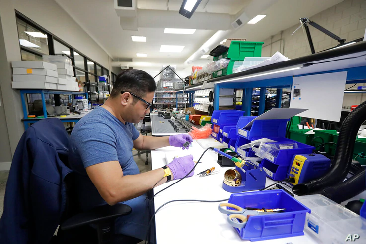 In this June 22, 2018, photo, Skydio tech assembler Alex Nakmoto works on the R1 flying camera drones in a laboratory in...