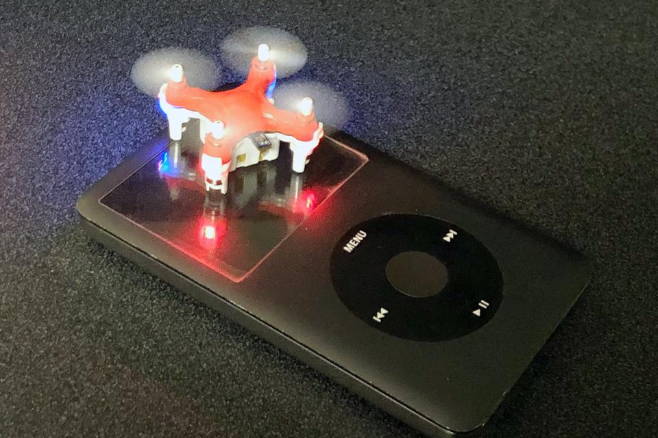 Tiny orange drone with propellers in motion.