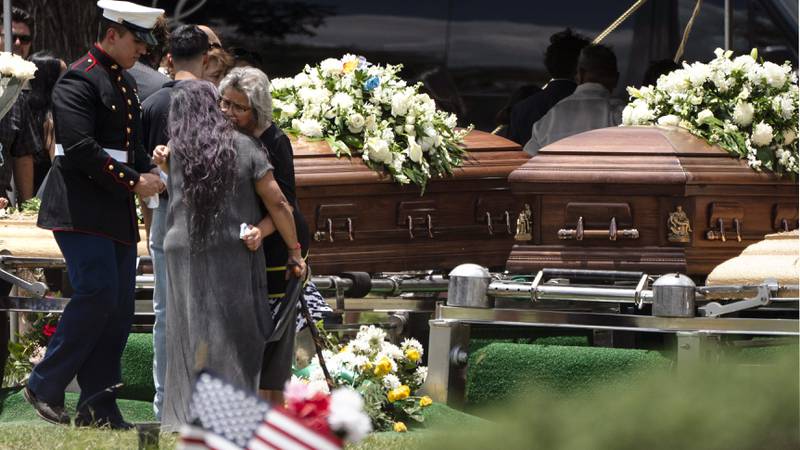 Two women comfort each other during the burial service for Irma Garcia and her husband Joe Garcia at Hillcrest Cemetery.