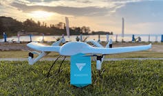 A delivery drone in shiny white pictured against a sunset.