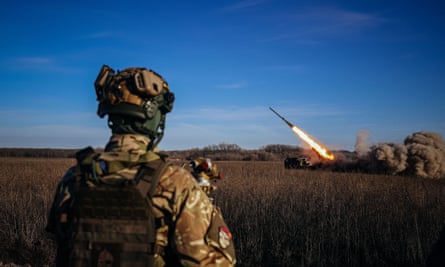 A Ukrainian soldier watches a self-propelled multiple rocket launcher firing towards Russian positions on the frontline in eastern Ukraine