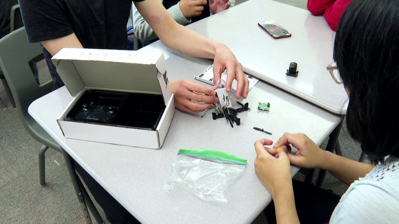 Two kids work to assemble electronic parts at a table.