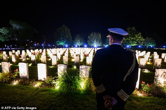 A British officer looks at illuminated graves at the Bayeux War Cemetery, in Bayeux