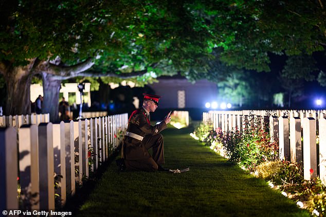 A British soldier photographs graves at the Bayeux War Cemetery, in Bayeux, France